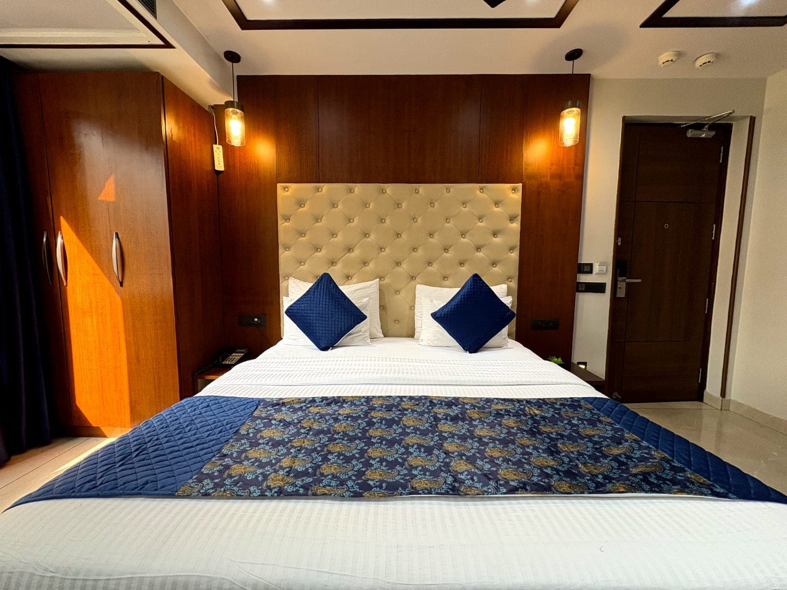 The Kavya Suite bedroom with a tufted headboard and blue accents